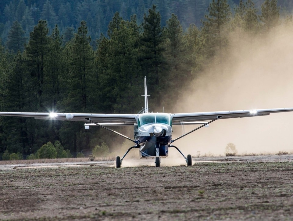A Cessna Grand Caravan EX takes off from a remote dirt airstrip