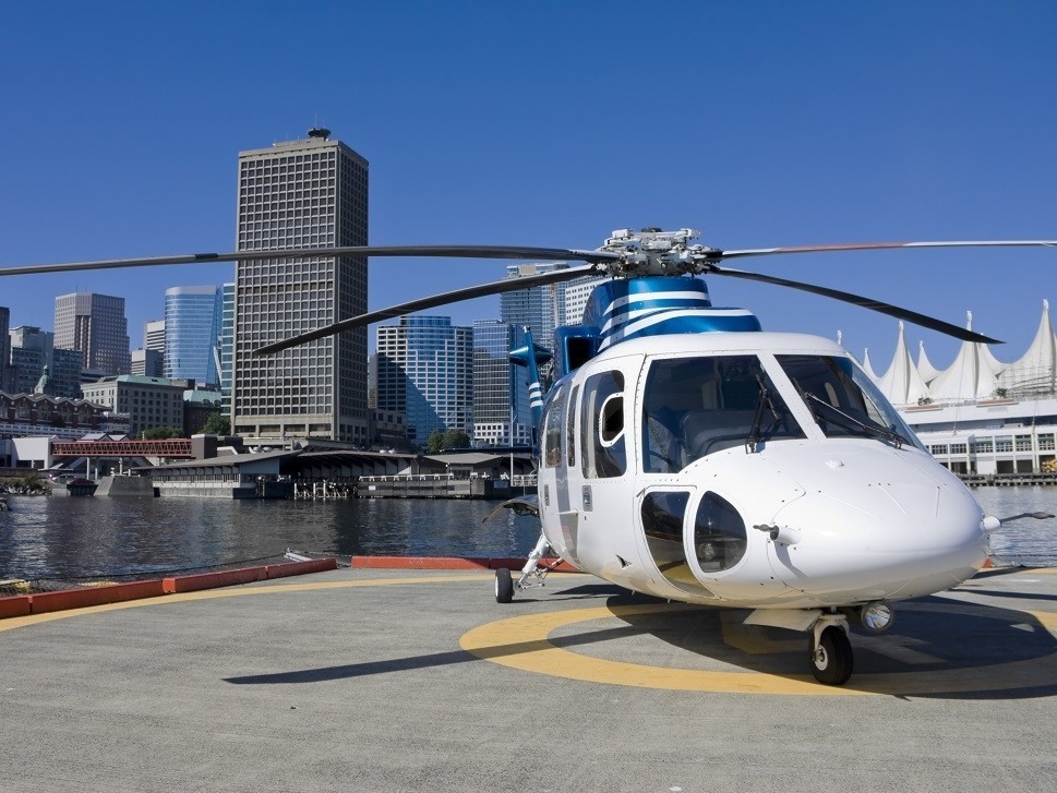 Turbine helicopter parked on heliport in front of skyscrapers