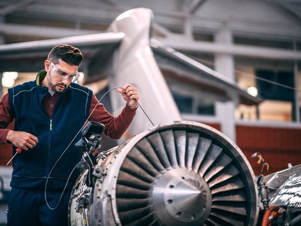 An airplane mechanic undertakes a borescope inspection