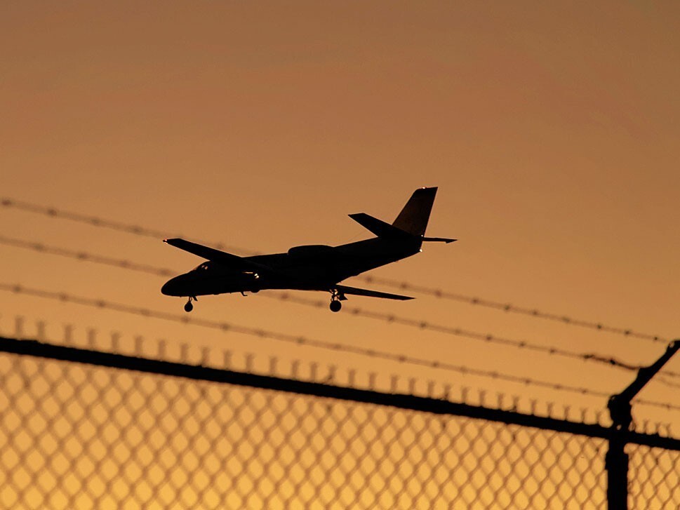Cessna Citation Jet flies over airport perimeter security fence
