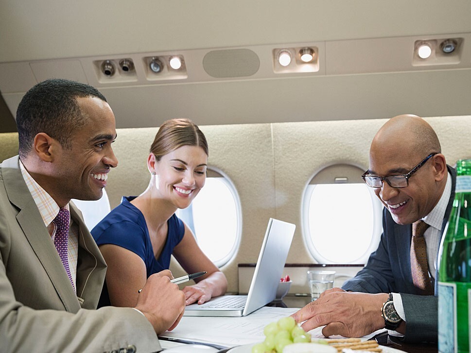 Three businesspeople talk and work in a private jet cabin